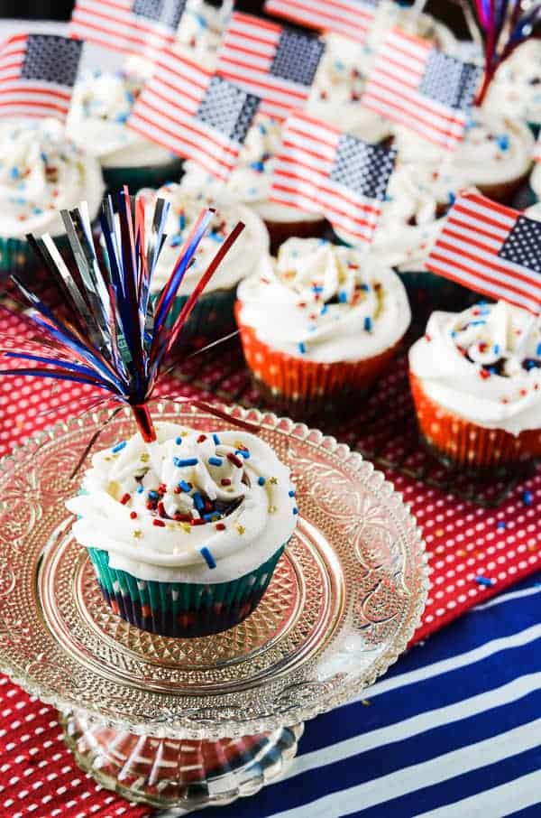 Firecracker Cupcakes | A classic vanilla cupcake, bursting with a slightly tart summer berry compote, and crowned with a halo of fluffy whipped cream cheese frosting.