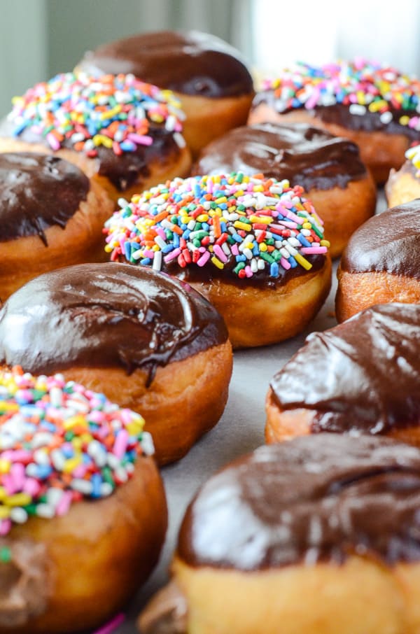 Nutella Cheesecake Donuts | Easy, fried yeast donuts made from scratch, made irresistible by a Nutella cheesecake filling and smooth chocolate ganache topping. Don't forget the sprinkles!