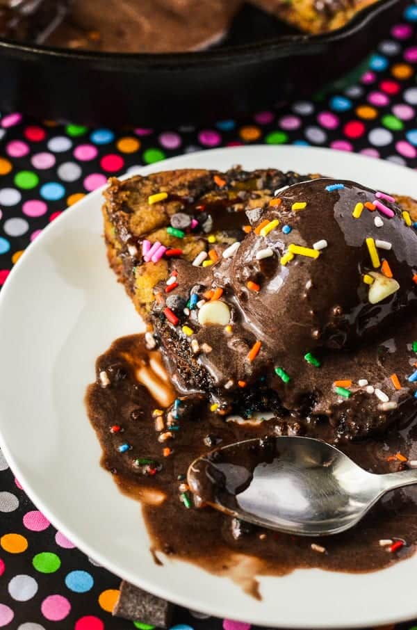 Triple Chocolate Chunk Funfetti Skillet Cookie | A celebration in every slice! Two kinds of cookie dough, stuffed with three kinds of chocolate & colorful sprinkles, then drizzled with caramel & even more chocolate!