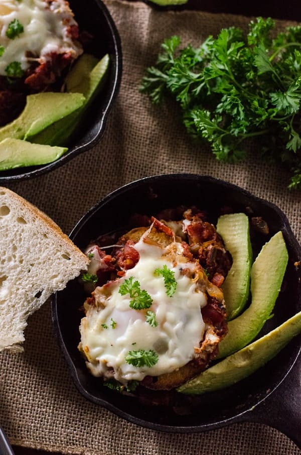 Eggs in Purgatory | Breakfast with a bit of burn! Eggs poached in a spicy, garlicky tomato sauce, served over crusty bread and with a side of cooling avocado slices. 