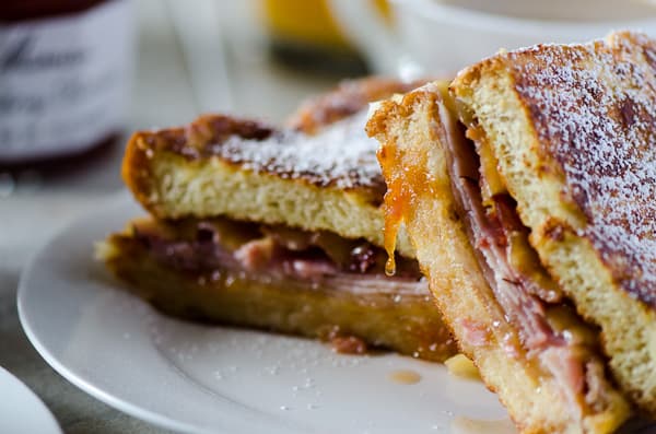 French Toast Monte Cristo | Truly the ultimate breakfast sandwich! Turkey, ham, bacon, lots of cheese, fried egg, and tasty preserves, tucked between two slices of thick, lightly sweetened challah French toast.