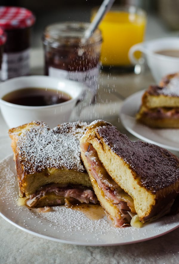 French Toast Monte Cristo | Truly the ultimate breakfast sandwich! Turkey, ham, bacon, lots of cheese, fried egg, and tasty preserves, tucked between two slices of thick, lightly sweetened challah French toast.