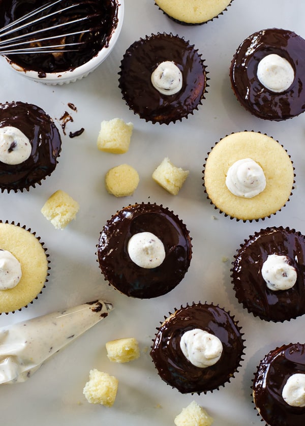 Cannoli Cupcakes with Chocolate Pistachio Crunch | Holy cannoli, what a cupcake! These vanilla-almond Cannoli Cupcakes are stuffed and topped with a classic sweet ricotta filling, glazed with a layer of chocolate ganache, and garnished with some pretty fancy food art.