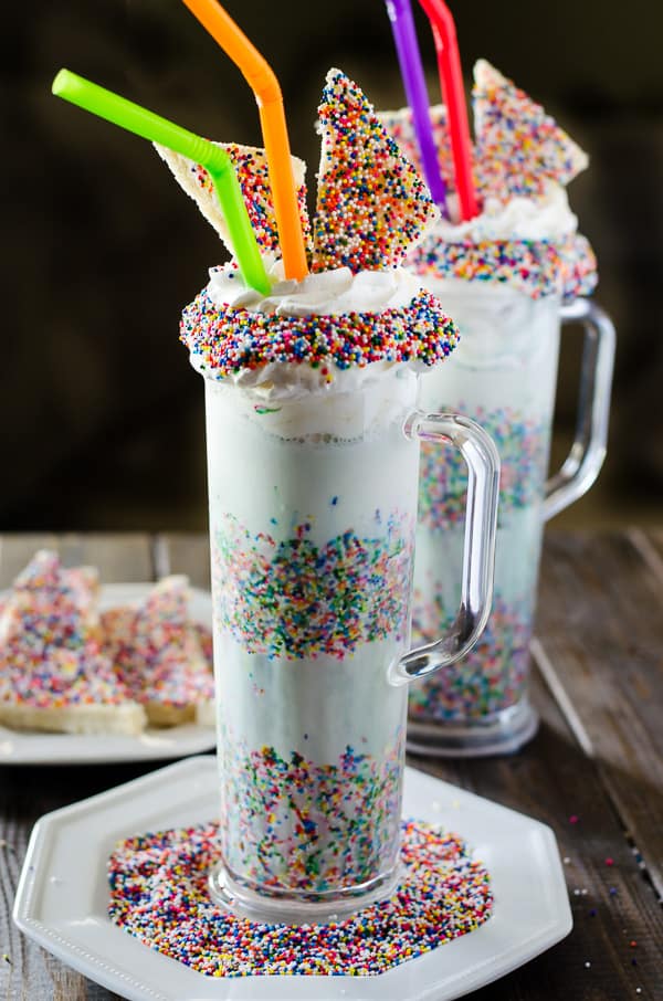 This Fairy Bread Funfetti Milkshake is bound to be a new after school favorite! Dress up those simple vanilla milkshakes with a mountain of whipped cream, tons of sprinkles, and some mini Fairy Bread slices!