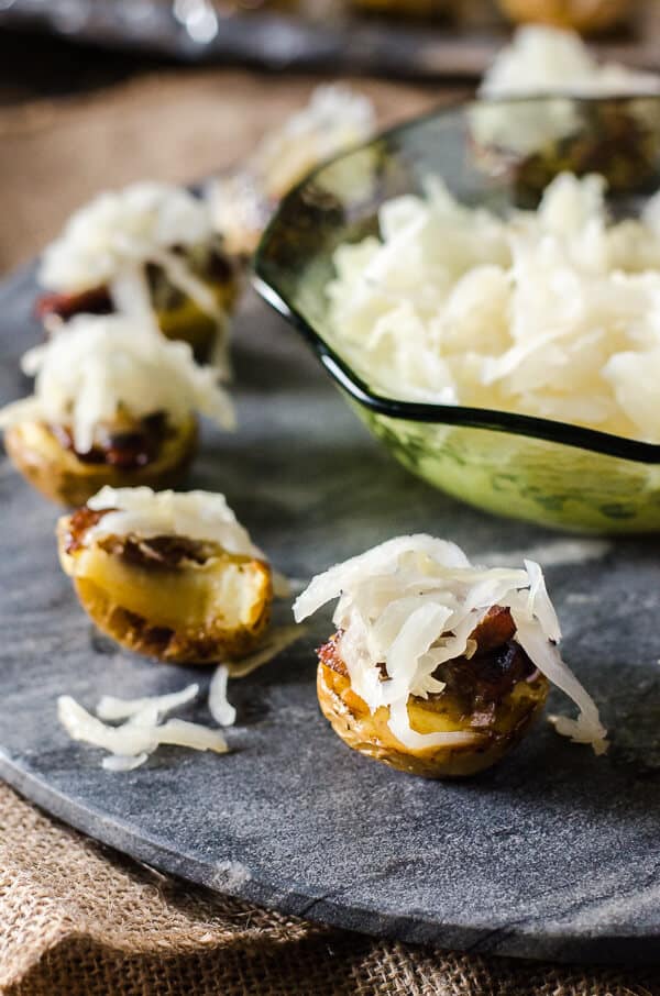 Fall and football season are almost here again, and these mini German Potato Skins can be found on the snack table! Super crispy baby potatoes covered in caramelized onions, beer-braised bratwurst, and a pile of sauerkraut make Game Day so much more delicious!