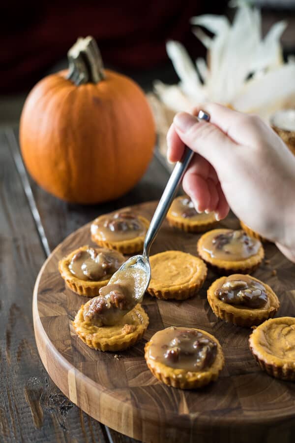 These adorable Mini Pumpkin Pecan Cheesecakes make indulgence nearly guilt-free! Tart-sized pumpkin cheesecakes topped with a praline pecan sauce and whipped cream are a seasonal two-bite treat!