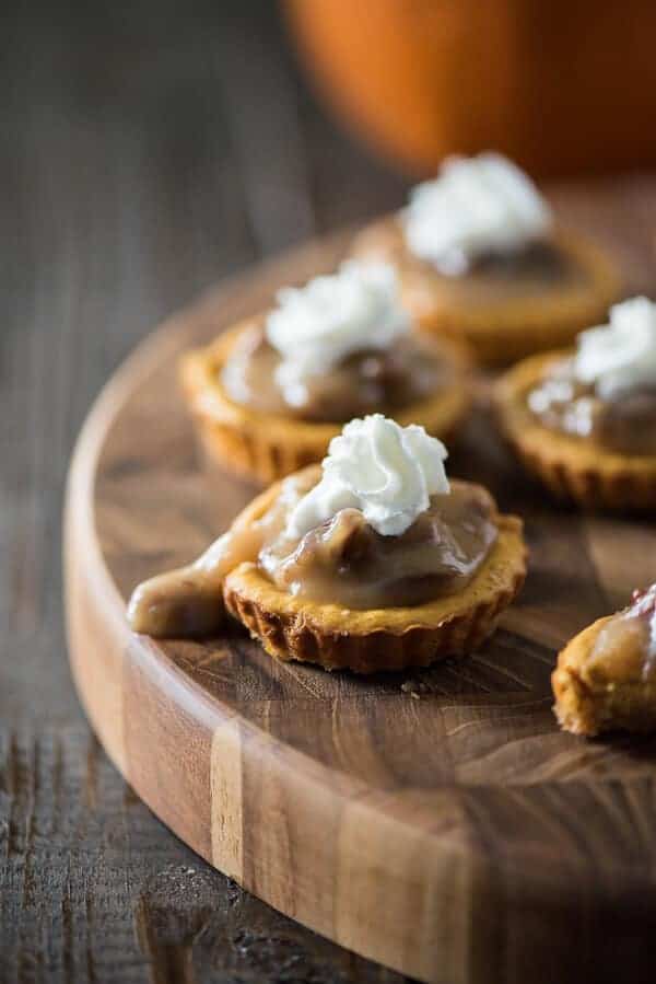 These adorable Mini Pumpkin Pecan Cheesecakes make indulgence nearly guilt-free! Tart-sized pumpkin cheesecakes topped with a praline pecan sauce and whipped cream are a seasonal two-bite treat!