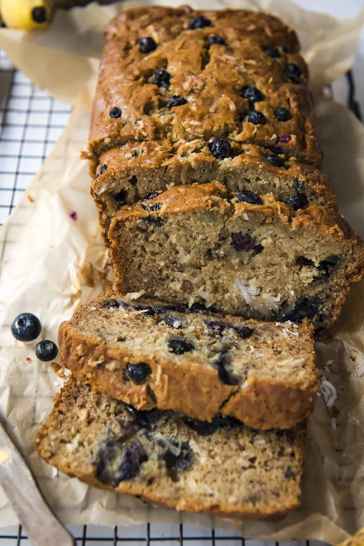 slices of blueberry coconut banana bread on a cooling rack
