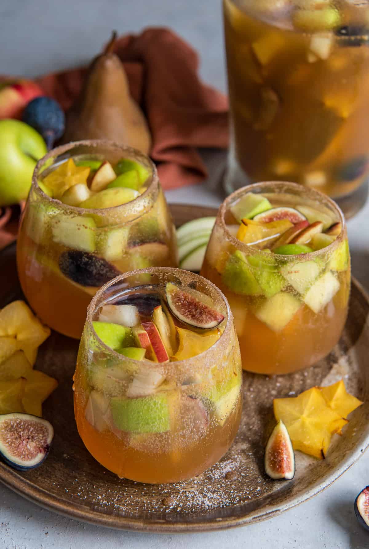 Three glasses of fall sangria with fruit and pears on a plate.