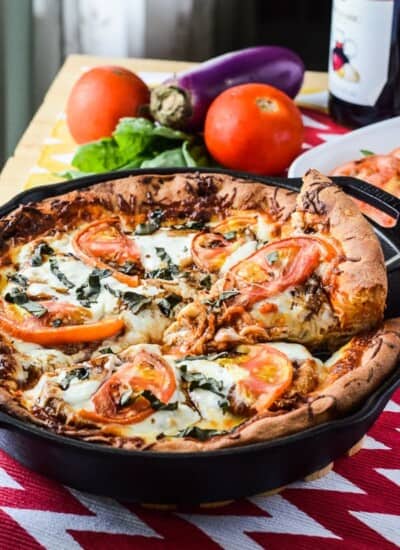 Eggplant Parmesan Caprese Skillet Pizza | A delicious deep dish caprese skillet pizza, layered with crispy baked eggplant parmesan, fresh tomatoes, spinach, & basil, and creamy mozzarella cheese.