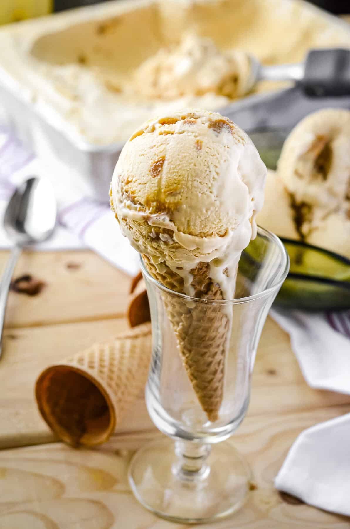 a scoop of dulce de leche ice cream in a sugar cone, set in a tall glass