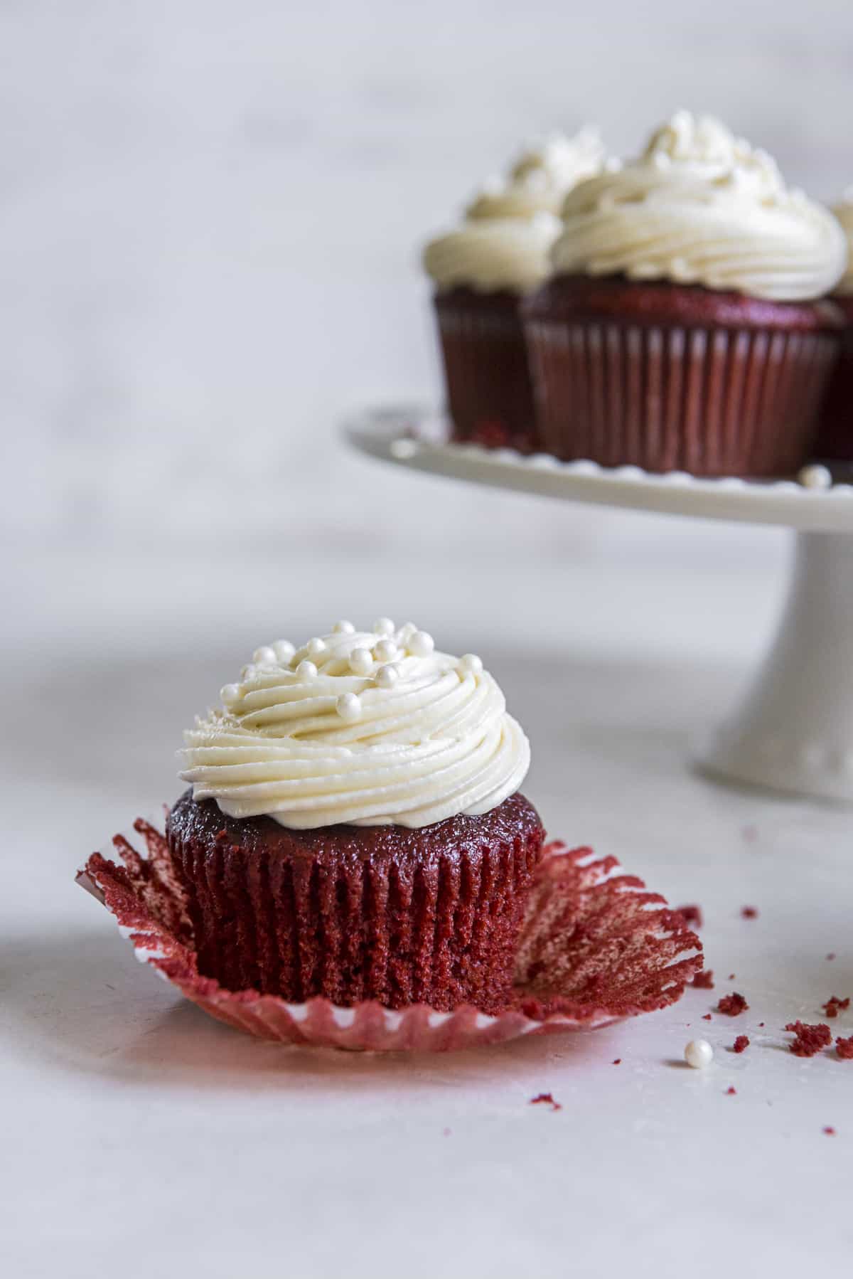 a frosted red velvet cupcake with the liner peeled back