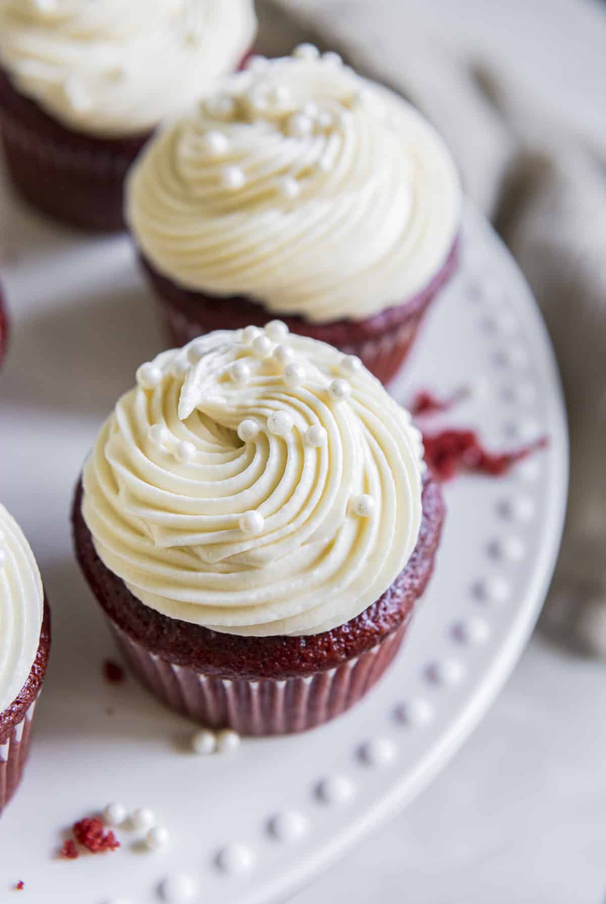 red velvet cupcakes topped with cream cheese frosting on a cake stand