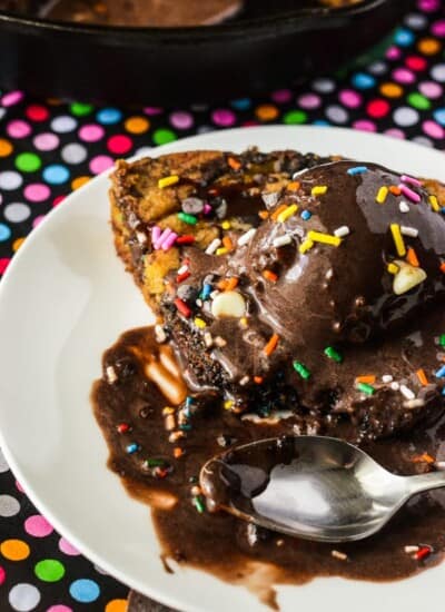 Triple Chocolate Chunk Funfetti Skillet Cookie | A celebration in every slice! Two kinds of cookie dough, stuffed with three kinds of chocolate & colorful sprinkles, then drizzled with caramel & even more chocolate!