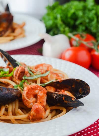 Seafood Fra Diavolo with Bucatini | Bucatini pasta, crowned with an array of fresh seafood that's bursting with spicy Italian flavor and lots of garlic - it's a spicy seafood spaghetti extravaganza!