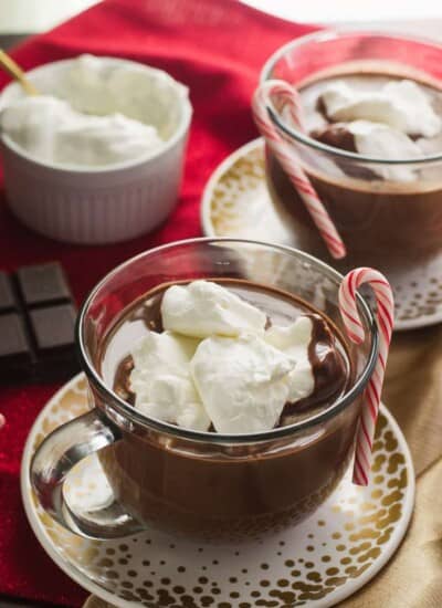 Two cups of French hot chocolate with whipped cream and candy canes.