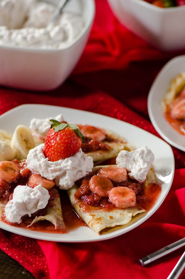Strawberry Banana Hazelnut Cream Crepes | A beautiful breakfast treat for your sweetheart! Florida strawberries, fresh bananas, and hazelnut spread, rolled up in thin, delicious crepes, topped off with homemade strawberry whipped cream!