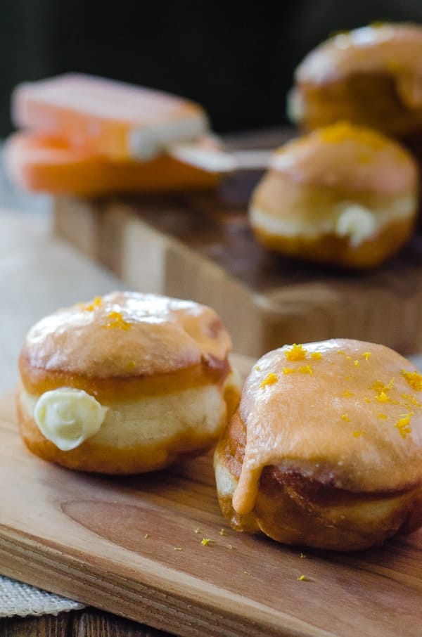 Orange Creamsicle Donuts | Your favorite childhood popsicle in donut form! Fried yeast donuts, stuffed with orange cream cheese filling, and topped with orange glaze. 