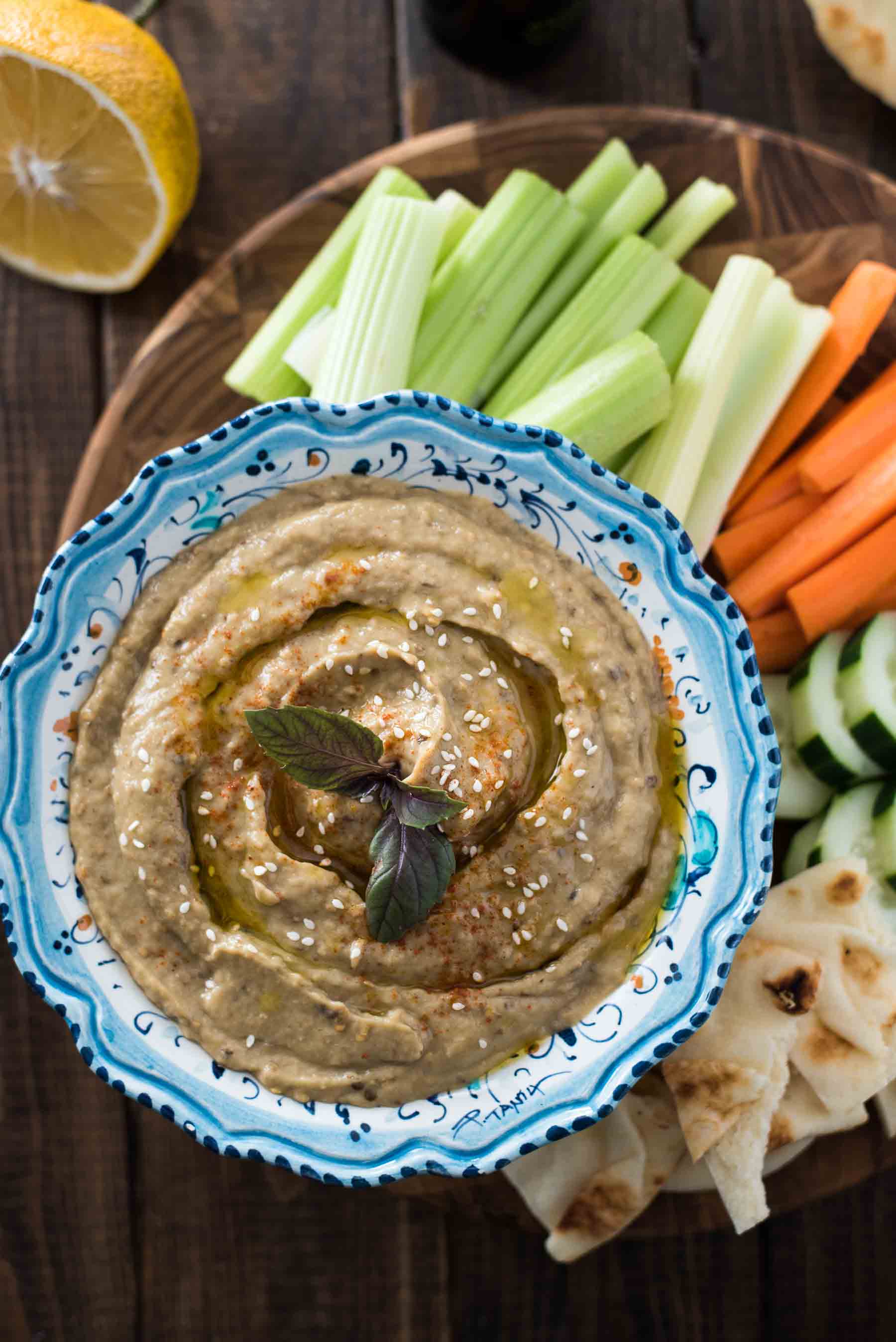 A simple appetizer that will thrill vegans as well as meat-eaters! Smokey, slightly chunky, and loaded with flavor, this traditional eggplant Baba Ganoush recipe is kicked up with a touch of cumin and paprika, plenty of garlic, and fresh Meyer lemon juice. 