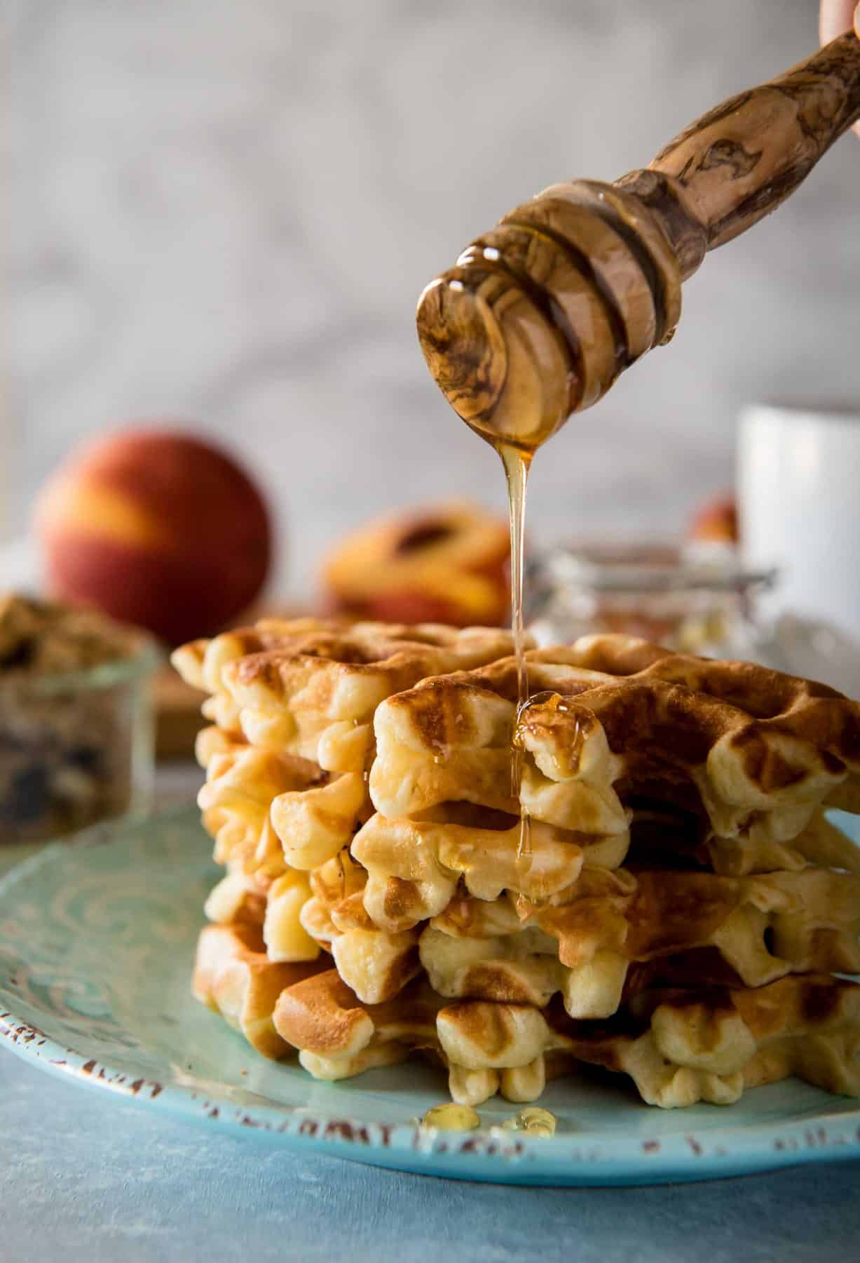 These deliciously easy Peach Cobbler Waffles with Honeyed Yogurt should be on your breakfast menu this weekend! Buttermilk waffles, lightly sweetened with yogurt & fresh peaches, then stacked and topped with honeyed yogurt and granola - nothing says summer quite like these!