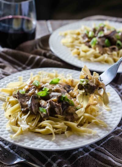 Mushroom stroganoff on a plate with a glass of wine.