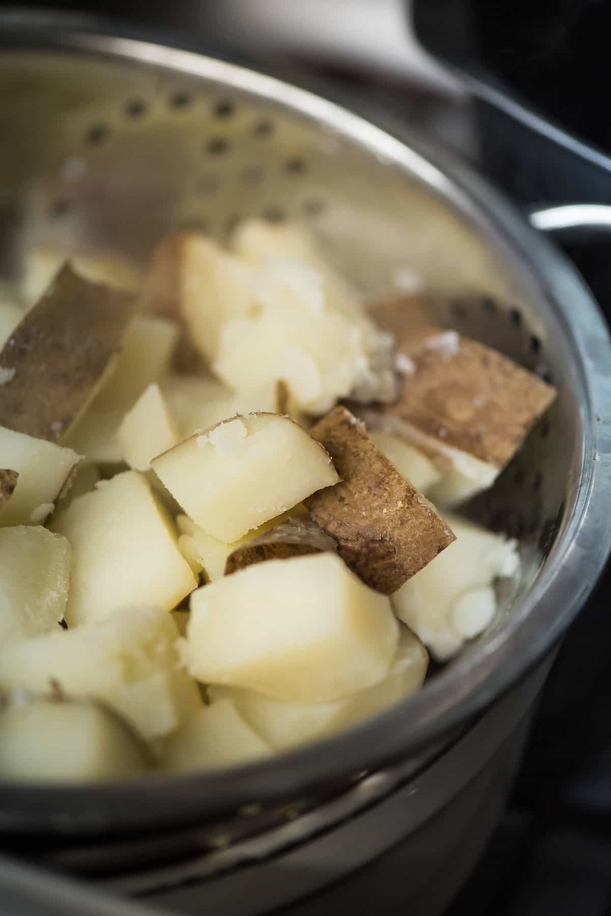 A colander with potatoes in it on a stove top