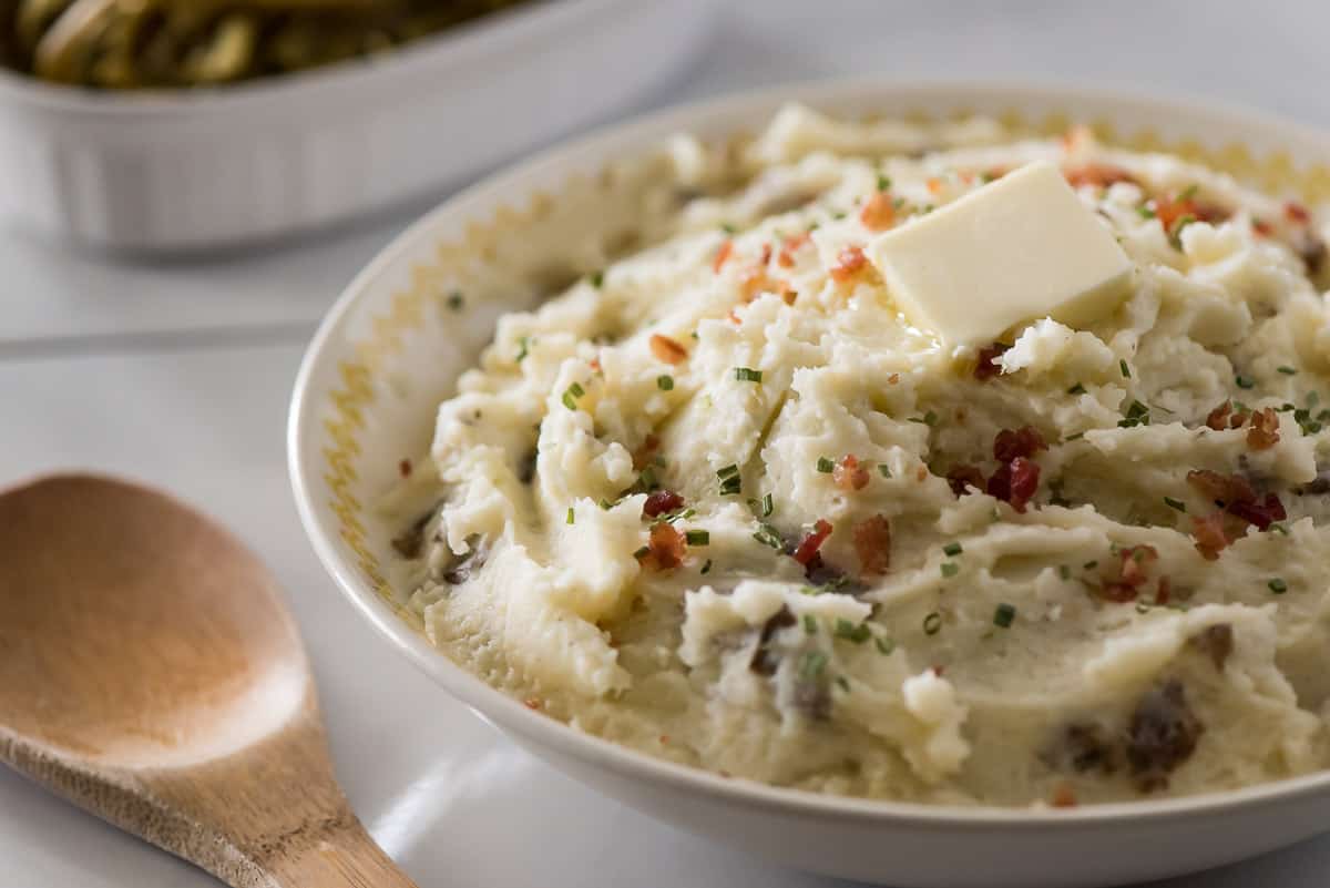 A bowl of mashed potatoes with bacon and butter, creating a delightful savory dish.