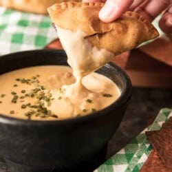 dipping Smoked Sausage and Peppers Empanadas in cheese dip