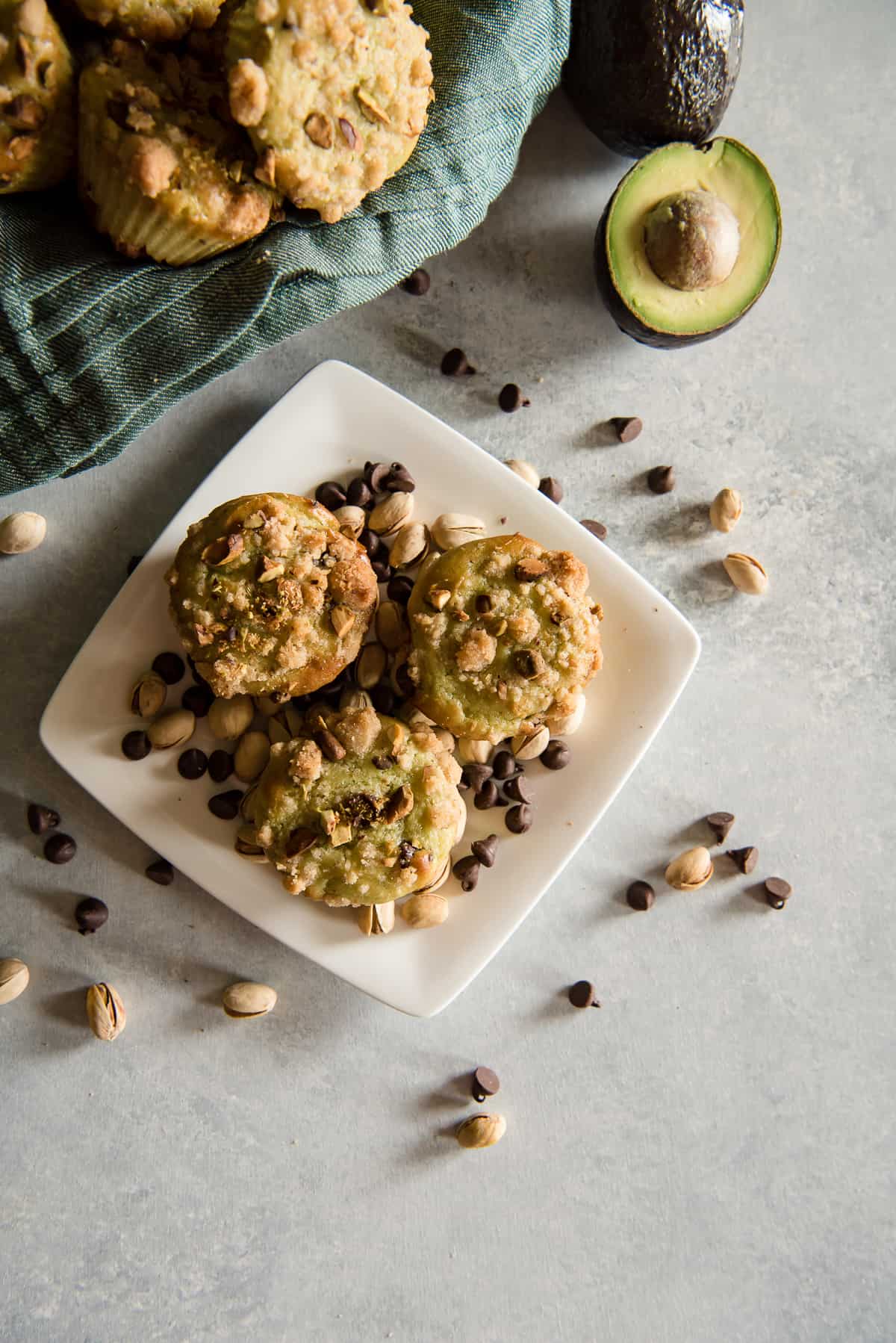 Avocado chocolate chip muffins with pistachios and avocados on a plate.