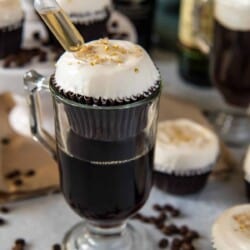 Irish coffee cupcakes with a spoon and coffee beans. These delicious treats are made with the rich flavors of Irish coffee, making them perfect for any coffee lover. The cupcakes are topped with a fluffy frosting