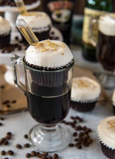 Irish coffee cupcakes with a spoon and coffee beans. These delicious treats are made with the rich flavors of Irish coffee, making them perfect for any coffee lover. The cupcakes are topped with a fluffy frosting