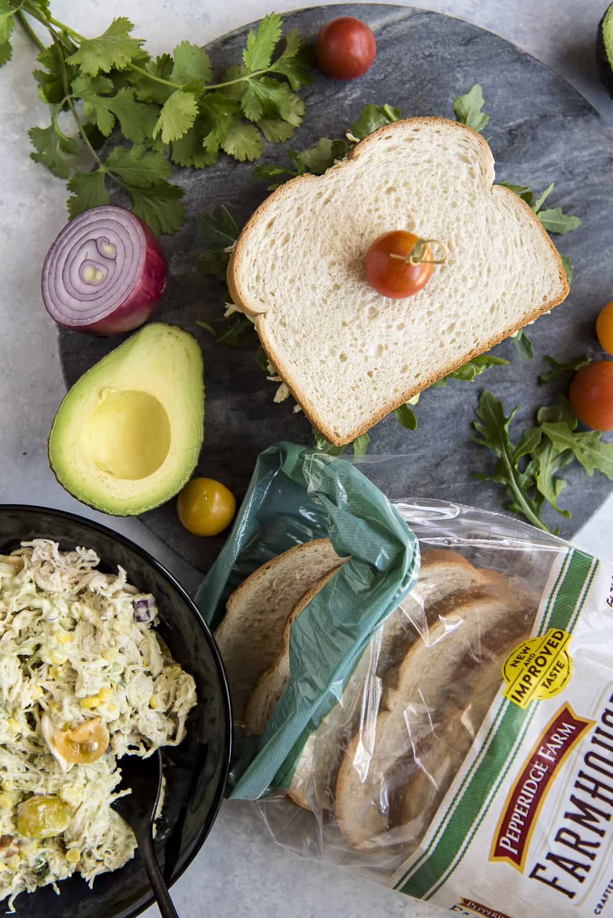 A bowl of chicken salad and a bag of bread on a table, perfect for making a delicious chicken salad sandwich.