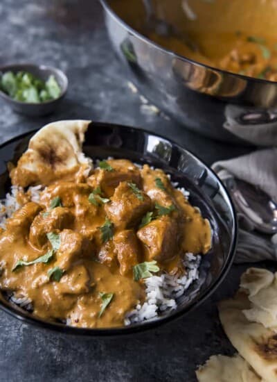 A bowl of chicken tikka masala with rice and naan.