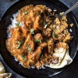 A bowl of chicken tikka masala with rice and a spoon.