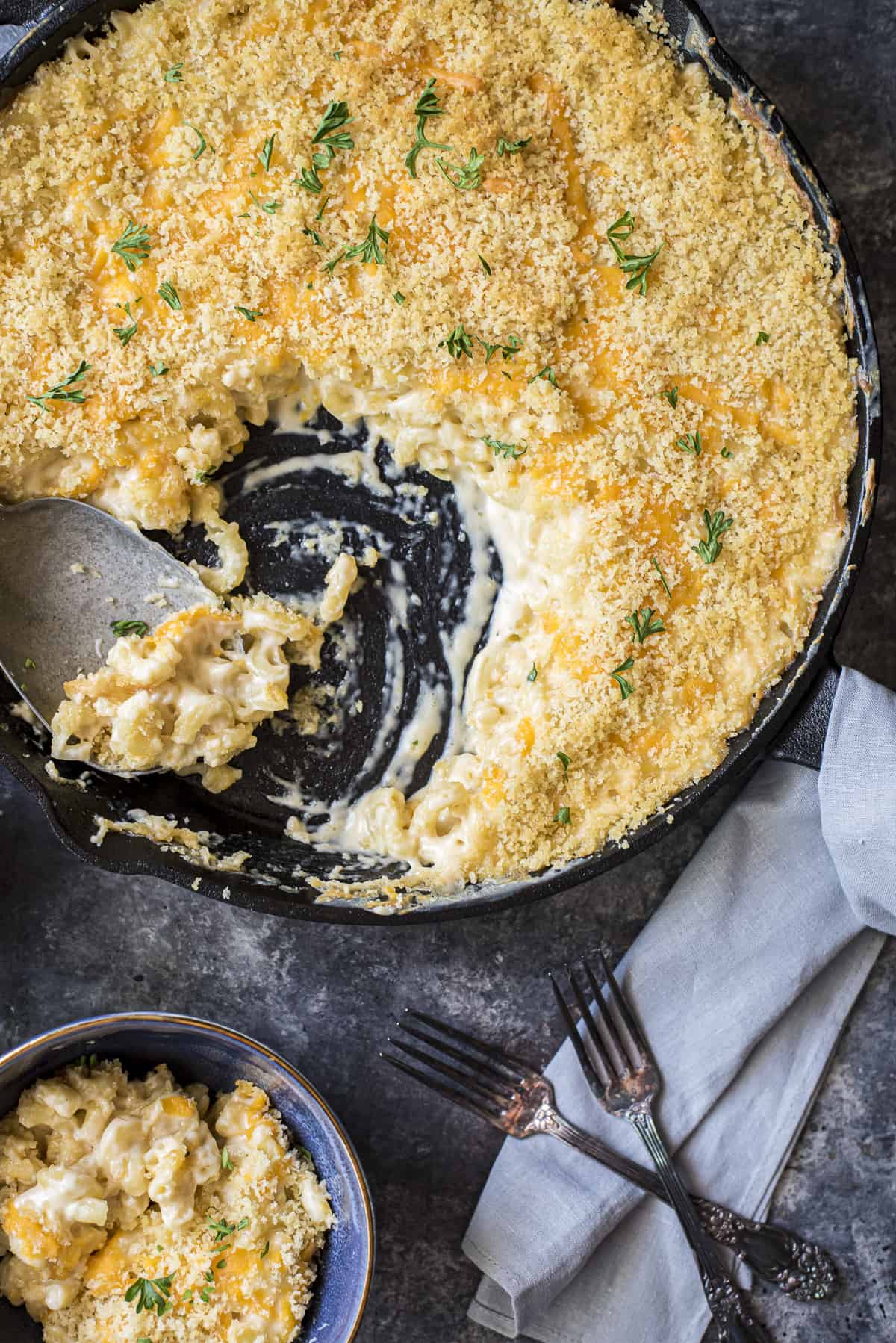 baked mac and cheese in a cast iron skillet with a scoop taken out