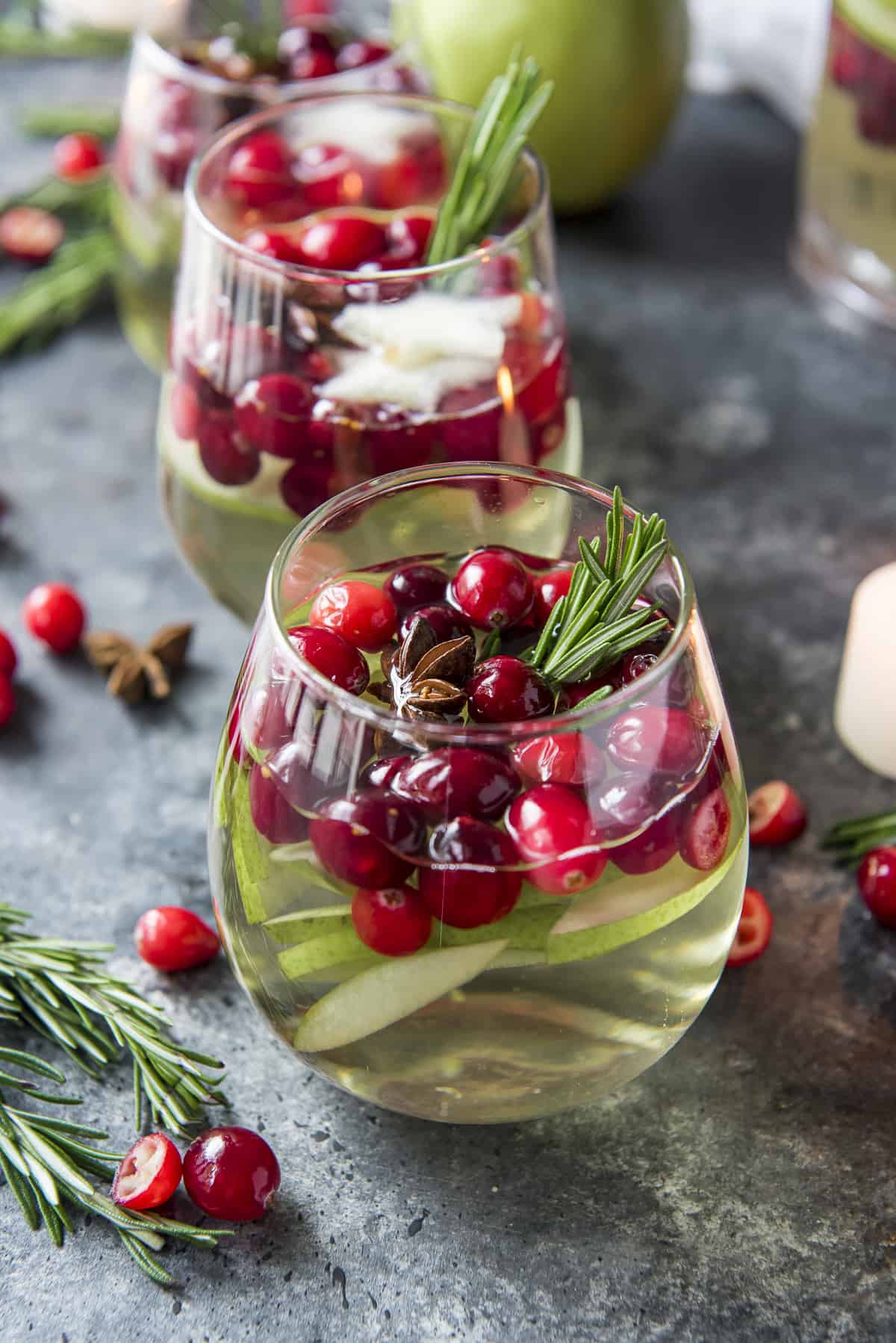 a stemless glass filled with white sangria and cranberries and pears