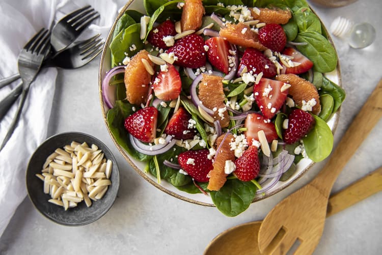 Top shot of a Citrus Strawberry Spinach Salad in a bowl with almonds on the side
