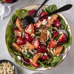 Two forks balanced in a bowl of Citrus Strawberry Spinach Salad