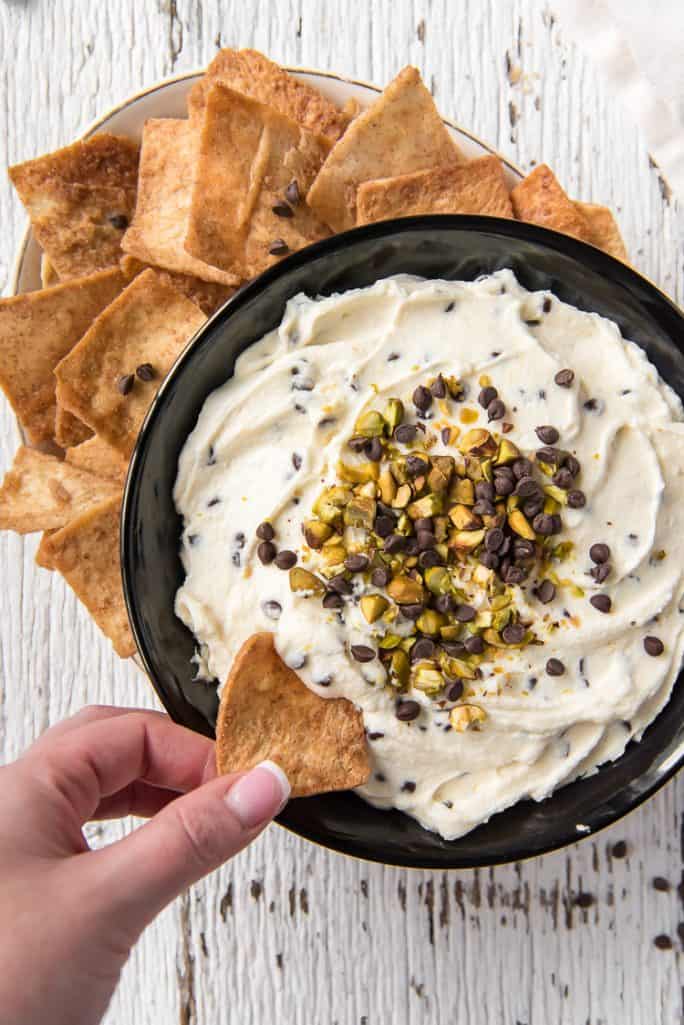 Dipping a chip into a bowl of Cannoli Dip