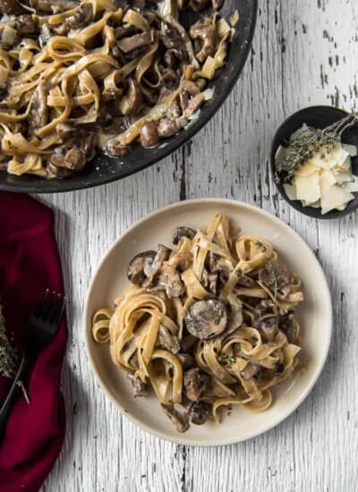 A plate and skillet full of Creamy Brown Butter Mushroom Pasta