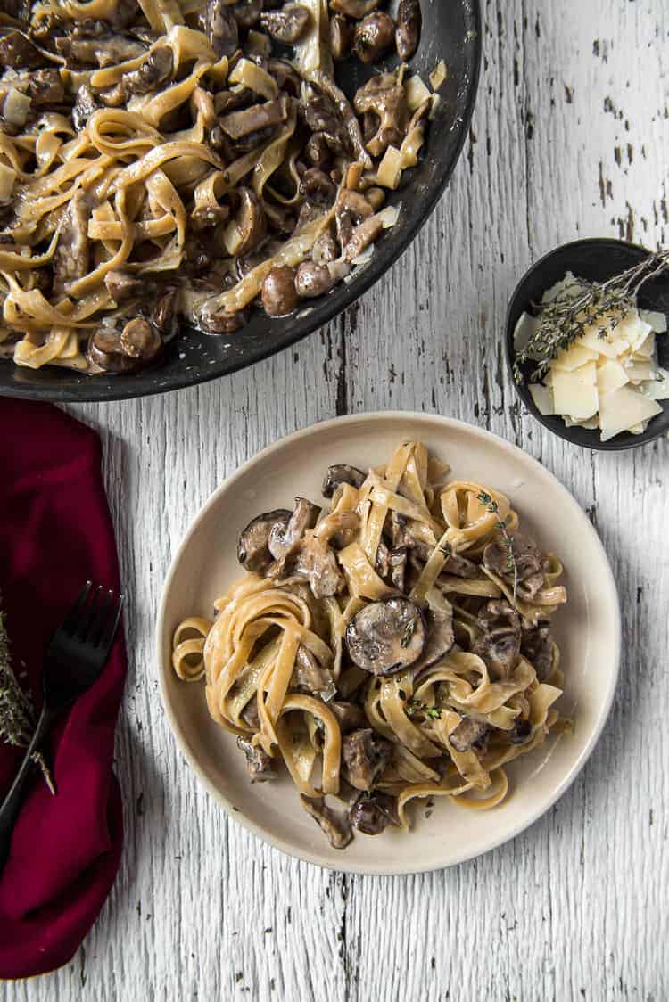 A plate and skillet full of Creamy Brown Butter Mushroom Pasta