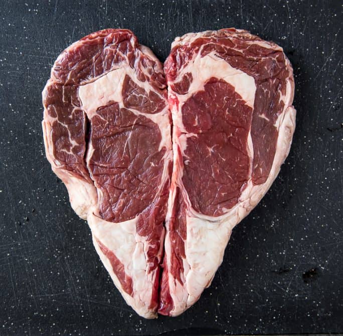 2 raw ribeye steaks in the shape or a heart