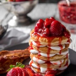 A gorgeous stack of Cheesecake Pancakes with strawberry syrup