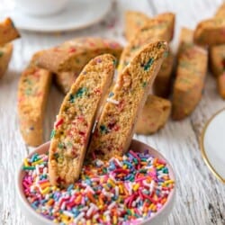 Rainbow biscotti in a bowl of sprinkles