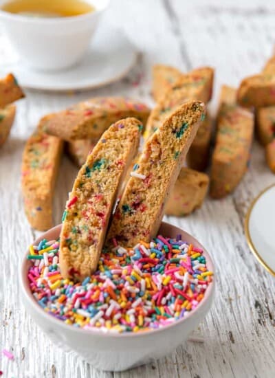 Rainbow biscotti in a bowl of sprinkles
