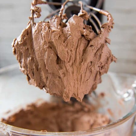 Whipped Chocolate Buttercream Frosting on a whip attached to a KitchenAid mixer