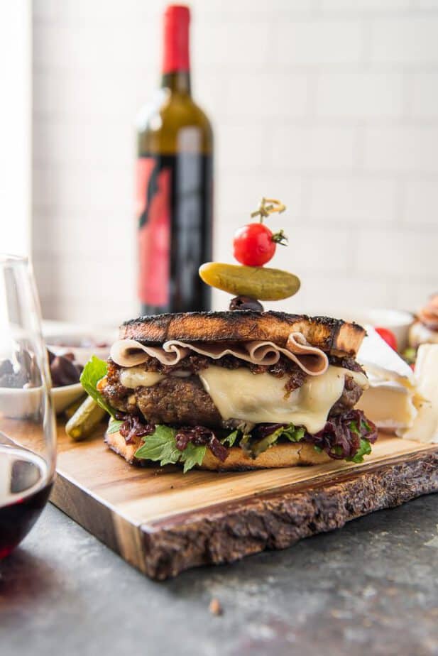 The Charcuterie Burger on a cutting board with a wine bottle in the background