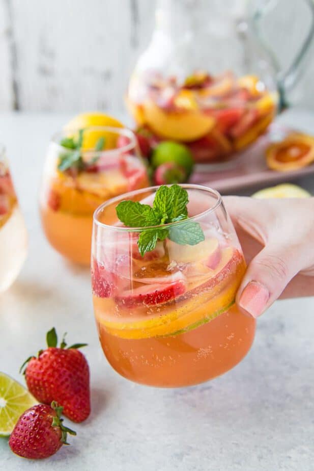 A hand holding a glass of Easy White Sangria