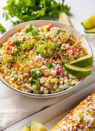Mexican corn salad in a bowl with a corn cob