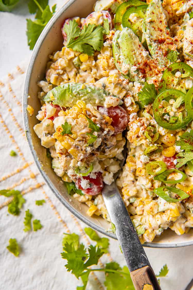 Creamy corn salad in a bowl with a spoon